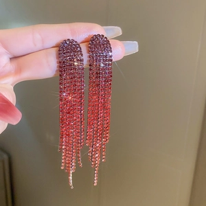 Close-up of long tassel earrings with sparkling rhinestones in red to orange gradient