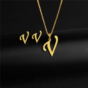 Detailed view of the gold-toned stylized letter V pendant necklace and matching stud earrings