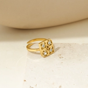 Macro shot of gold square open ring with clover cut-outs and inlaid clear zircon stones