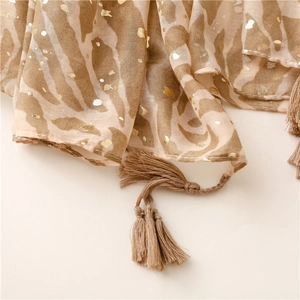 Close-up of animal print scarf with gold foil details and woven fringe trim texture