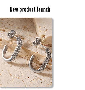 Detailed close-up of silver U-shaped earrings with sparkling white rhinestones on stone