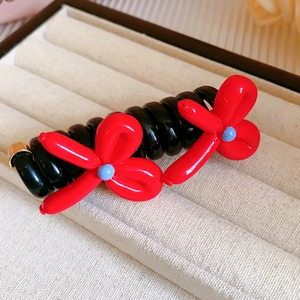 Détail d'élastique spirale noir avec fleurs rouges et fermoir en métal doré