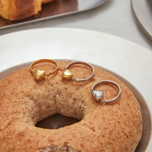 Drei Herzanhänger-Ringe in Gold und Silber präsentiert auf einem frischen Bagel
