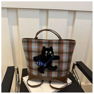 Detail of plaid fabric tote bag featuring a cute black cat embroidery and leather handles