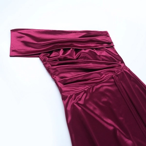 Détails de la robe en satin bordeaux montrant le design plissé à une épaule élégante