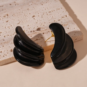 Macro shot of three-tier black resin geometric earrings with glossy finish on stone