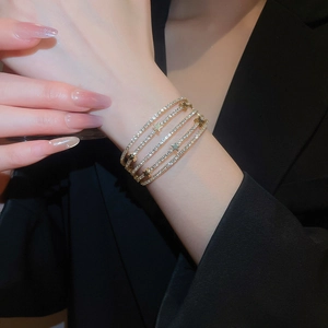 Close-up of a layered gold bracelet featuring sparkling crystals and star charms on wrist