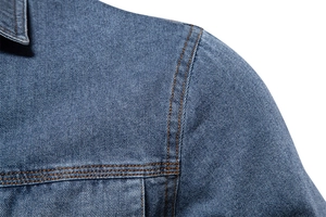 Détail de la double couture orange et de la texture sur l'épaule d'une chemise en denim bleu