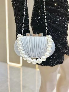 Silberne Abend-Clutch mit großem Perlengriff und Metallkette auf schwarzem Kleid