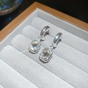 Detail shot of silver-colored earrings featuring square-cut zircons in a velvet box