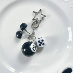 Silver keychain with black cherries, 8-ball charm, dice and star on white ceramic plate