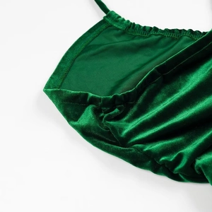 Detailweergave van de groene fluwelen stof en geplooide bandjes op de rugloze jurk