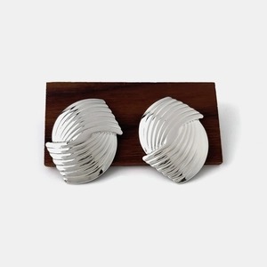 Macro shot of silver geometric earrings with shell texture on a dark wooden surface