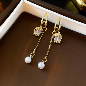 Detail of elegant gold tulip earrings with cubic zirconia, long tassels, and white pearls