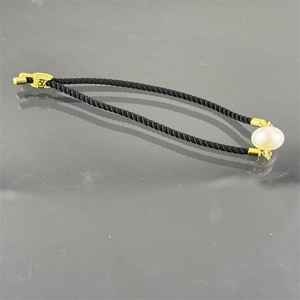 Detailed view of black Milan cord bracelet with a large white pearl and gold clasp