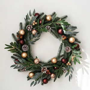 Premium Christmas wreath with pine needles, red ornaments and pinecones on a wall