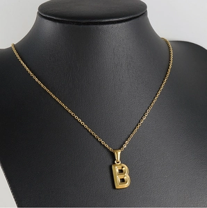 Detail of 18K gold letter B pendant necklace displayed on a black neck mannequin