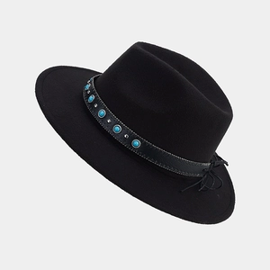Détail d'un fedora noir avec perles turquoise, clous en métal et bande à franges