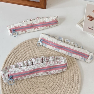 Floral pencil case with bow detail, ruffle edges and ring zipper on woven mat