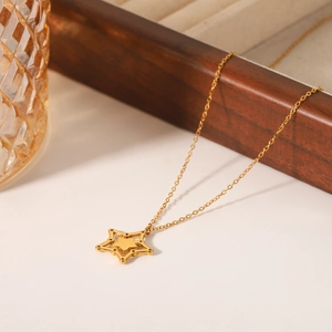 Elegant gold stainless steel star pendant necklace with hollow design on warm background