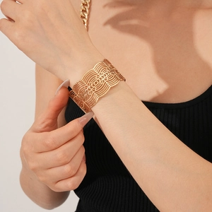 Détail d'un bracelet manchette doré large avec des motifs géométriques évidés chic