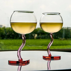 Creative heart glass goblets with twisted purple and pink stems on a reflective outdoor table
