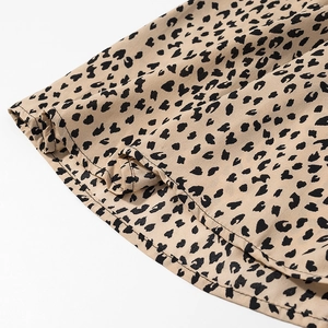 Macro shot of the ruffled hem and leopard print texture on a satin dress fabric