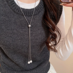Collier à pompon en perles argenté ajustable porté sur un pull pour un look chic