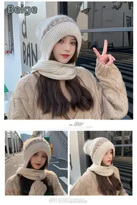 Dettaglio del cappuccio in maglia beige con pompon in pelliccia e sciarpa integrata