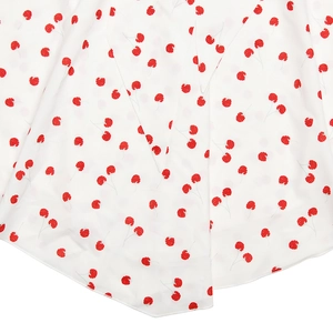Détail du tissu blanc avec petits motifs floraux rouges et couture d'ourlet sur la robe