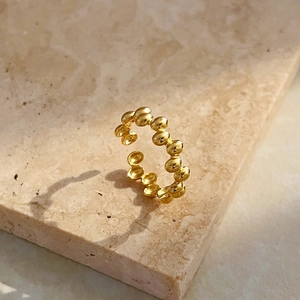 Detailed view of adjustable golden beaded chain open ring on a natural stone base