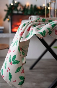 Detailed drape of Christmas tablecloth with holly leaves and red berry prints on fabric