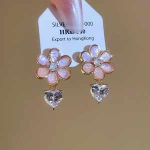 Detail of flower earrings with pink resin petals and a sparkling heart-shaped zircon drop