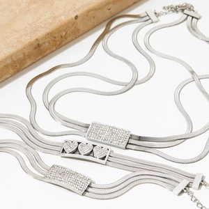 Silver multi-layer stainless steel heart necklace and bracelet set on a white background