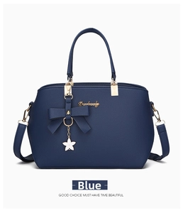 Detail of blue textured leather handbag with bow charm and adjustable shoulder strap