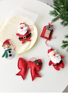 Set of handmade felt Christmas ornaments including Santa, snowman, and a red bow hanger