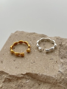 Detailed view of sterling silver rings with wave texture in gold and silver finish