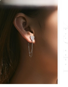 Detailed view of silver heart earrings with sparkling stones and long dangling chains on model