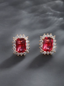 Macro view of vintage gold earrings featuring rectangle ruby-tone stones and white crystals