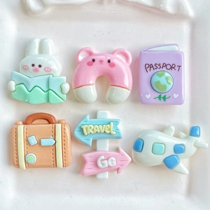 Flat lay view of colorful resin travel charms including passport, suitcase, and airplane