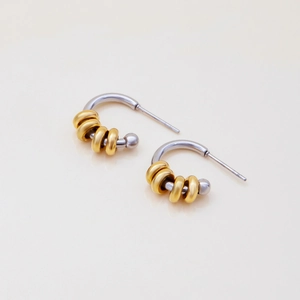 Close-up of modern two-tone C-shaped earrings with gold rings on silver curved pins