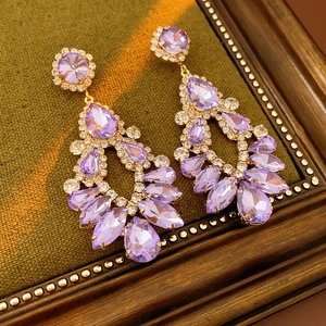 Macro shot of purple crystal drop earrings with gold base on a decorative tray