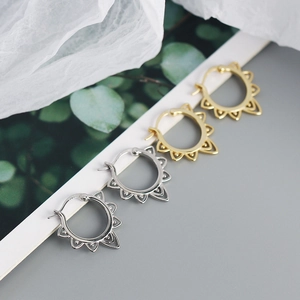 Close-up of vintage metal hoop earrings with hollow sun patterns in gold and silver