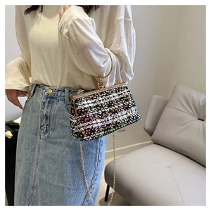 Detail of colorful sequin crossbody bag featuring a gold chain and metal ring handle