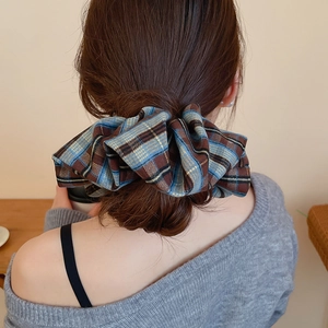 Close-up of a plaid scrunchie in brown and blue patterns on a stylish updo hairstyle