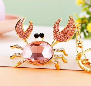Macro shot of gold crab keychain featuring pink oval gemstone and sparkling crystal legs