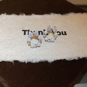 Detail showing silver bow stud earrings with white pearls and sparkling zircons