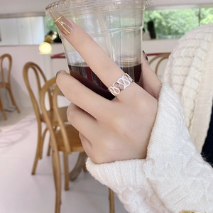 Close-up of hollow chain-link silver ring on hand in a cozy cafe setting