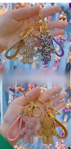 Close-up of sparkling rhinestone bear keychains with gold metal rings and leather straps