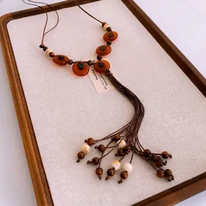 Retro ethnic style necklace with amber beads and long tassel in a wooden tray